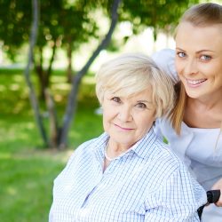 Female caregiver walking with senior patient in park